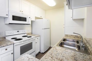 Northridge apartment for rent - A kitchen with white appliances and granite countertops.