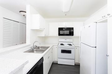 Studio City apartment for rent - A white kitchen with a black microwave and oven.