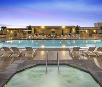 Evening pool deck with spa and lounge chairs