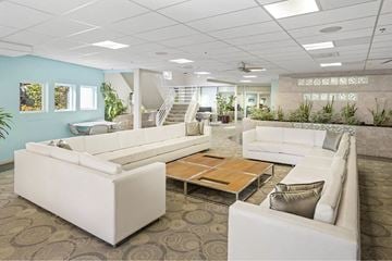 San Diego apartment for rent - A spacious living room with white furniture and a staircase in the background.