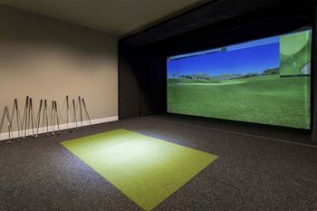 Indoor golf simulator room with projection screen