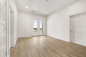 Idaho Falls apartment for rent - A room with white walls and wooden flooring, with a view of a building outside the window.