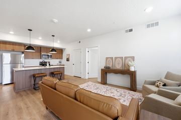 Layton apartment for rent - A modern living room with a brown sofa and a kitchen area in the background.