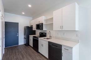 Provo apartment for rent - a kitchen with white cabinets and black appliances and a black refrigerator