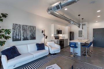 Provo apartment for rent - A modern living room with a white couch and a bar area.