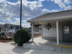 Laramie apartment for rent - A small building with a porch and a sign on the sidewalk.