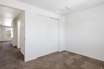St.George apartment for rent - a living room with white walls and carpet and a door to a hallway