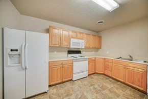 Rexburg apartment for rent - a kitchen with white appliances and wooden cabinets