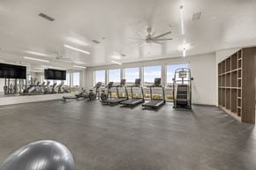 Idaho Falls apartment for rent - A spacious gym with treadmills, elliptical machines, and a fan.
