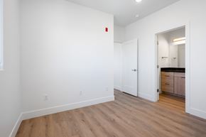 Hurricane apartment for rent - a bedroom with white walls and wood flooring and a door to a bathroom