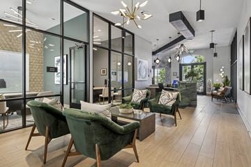 Lone Tree apartment for rent - A modern living room with green velvet chairs and a glass wall.