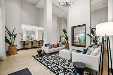 Plantation apartment for rent - A living room with a white couch, a black and white rug, and a painting on the wall.