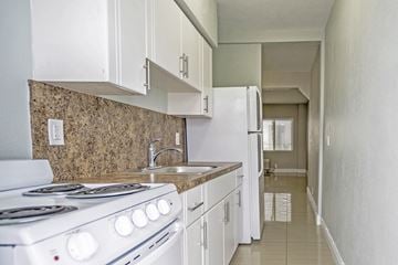 Miami Beach apartment for rent - A kitchen with a white stove and white cabinets.