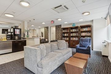 Philadelphia apartment for rent - A living room with a grey couch, a blue armchair, and a bookshelf filled with books.