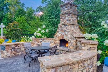 Outdoor lounge with grilling stations, seating and a wood-burning fire place