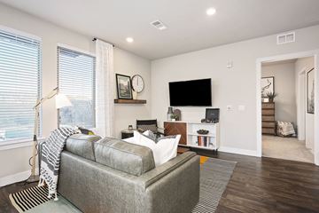 Golden apartment for rent - A living room with a grey couch and a flat screen TV mounted on the wall.