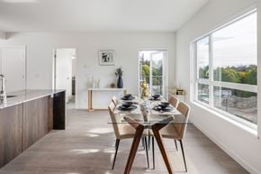 Colwood apartment for rent - a dining room with a glass table and chairs and a kitchen with large windows