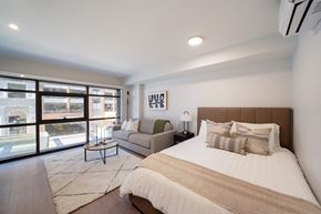 Vancouver apartment for rent - A bedroom with a large bed and a view of the street outside.