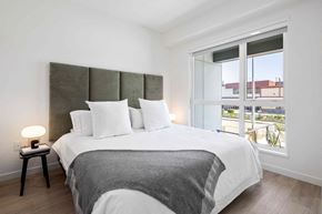 Richmond apartment for rent - A bedroom with a large bed and a window overlooking a balcony.