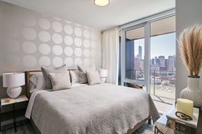 Chicago apartment for rent - A bedroom with a large bed and a view of the city.