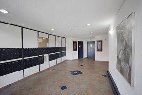 Chilliwack apartment for rent - A hallway with a row of mailboxes on the left and a painting on the right.