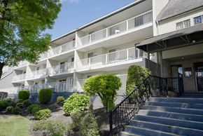 Chilliwack apartment for rent - A building with a balcony and stairs leading to the entrance.