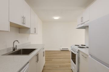 Surrey apartment for rent - A kitchen with white cabinets and a stove top oven.