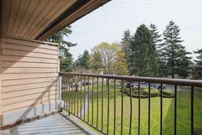 Surrey apartment for rent - A balcony with a metal railing overlooking a grassy area.