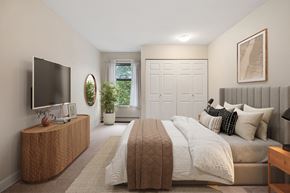 Coquitlam apartment for rent - A bedroom with a large bed and a television on a wooden stand.