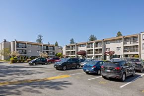 Surrey apartment for rent - A parking lot with cars and apartment buildings in the background.