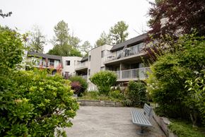 Burnaby apartment for rent - A grey bench sits in front of a building.