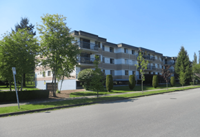 Surrey apartment for rent - Apartment building with trees and bushes in front.