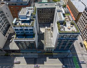 Vancouver apartment for rent - A tall building with a green roof is surrounded by other buildings.