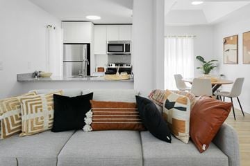 Phoenix apartment for rent - A modern living room with a grey couch and a kitchen in the background.
