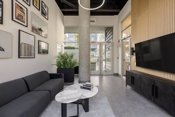 Vancouver apartment for rent - A living room with a grey couch, a white coffee table, and a television on the right side.