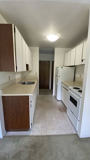 Surrey apartment for rent - A kitchen with white appliances and brown cabinets.