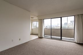 Surrey apartment for rent - A room with a carpeted floor and a large window with a view of buildings outside.