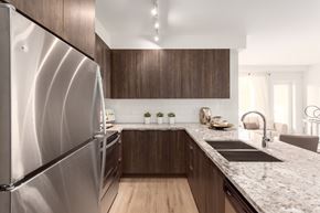 New Westminster apartment for rent - A modern kitchen with a stainless steel refrigerator and wooden cabinets.