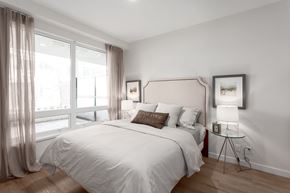 New Westminster apartment for rent - A bedroom with a large bed and a window with curtains.