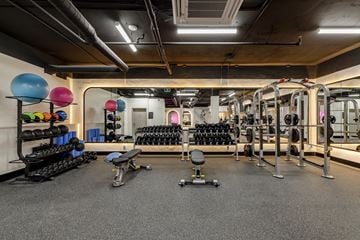 Vancouver apartment for rent - A gym with a variety of equipment including dumbbells, weight plates, and a bench.
