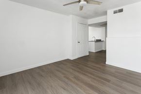 Phoenix apartment for rent - A room with a white ceiling and a fan, and a kitchen area with a stove and a refrigerator.