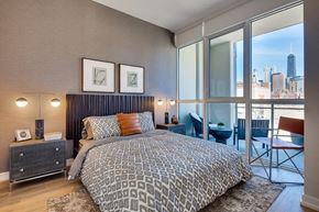 Chicago apartment for rent - A bedroom with a large bed and a view of the city.