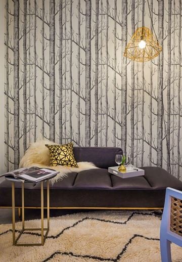 Chicago apartment for rent - A living room with a grey couch and a tree patterned wallpaper.