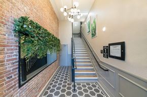 Los Angeles apartment for rent - A staircase with a brick wall on the left and a green plant on the wall.