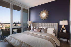 Chicago apartment for rent - A bedroom with a large bed and a view of the city.