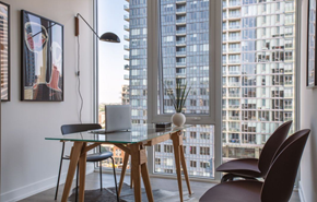 Chicago apartment for rent - A modern dining room with a glass table and chairs, a laptop, a plant, and a framed picture on the wall.