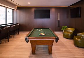 Chicago apartment for rent - A pool table in a room with leather chairs and a television mounted on the wall.