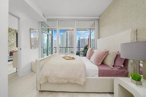 Chicago apartment for rent - A bedroom with a large bed and a view of the city.