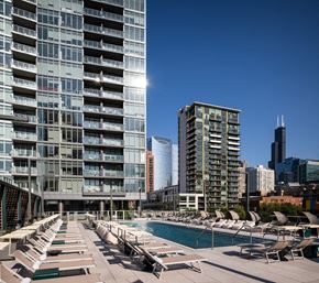 Chicago apartment for rent - A sunny day at a rooftop pool with lounge chairs and a view of the city skyline.