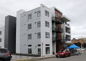 Bremerton apartment for rent - A modern multi-story building with a red car parked in front.